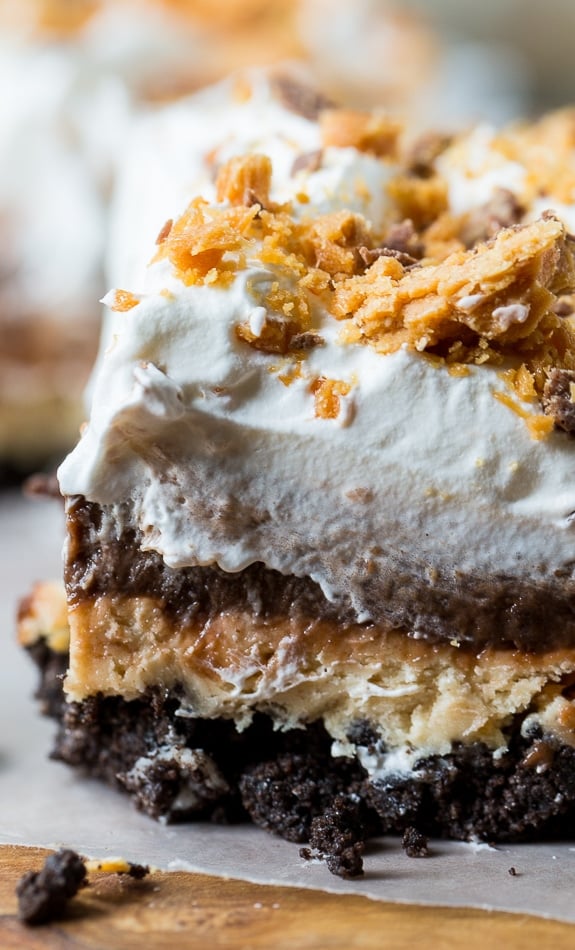 Butterfinger Chocolate Lush  has an oreo cookie crumb crust, a creamy peanut butter layer with crushed Butterfingers, a chocolate pudding layer, and a Cool Whip topping.