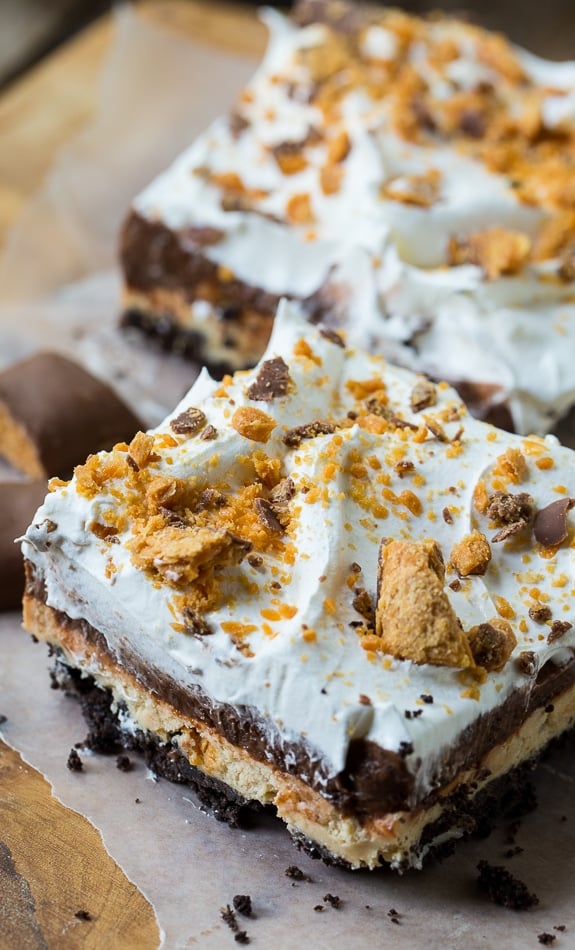 Butterfinger Chocolate Lush has an oreo cookie crumb crust, a peanut butter layer with crushed butterfingers, a chocolate pudding layer, and a Cool Whip topping.