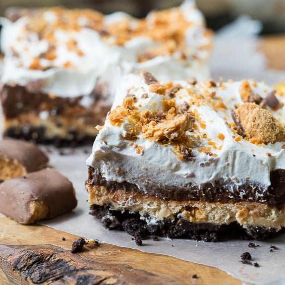 This Butterfinger Chocolate Lush has an oreo cookie crumb crust, a peanut butter layer with crushed butterfingers, a chocolate pudding layer, and Cool Whip on top.