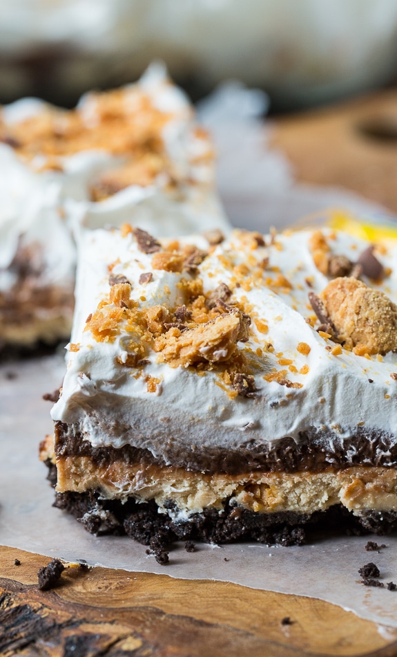 Butterfinger Chocolate Lush has an oreo cookie crumb crust, a creamy peanut butter layer with crushed Butterfingers, a chocolate pudding layer, and a Cool Whip topping.