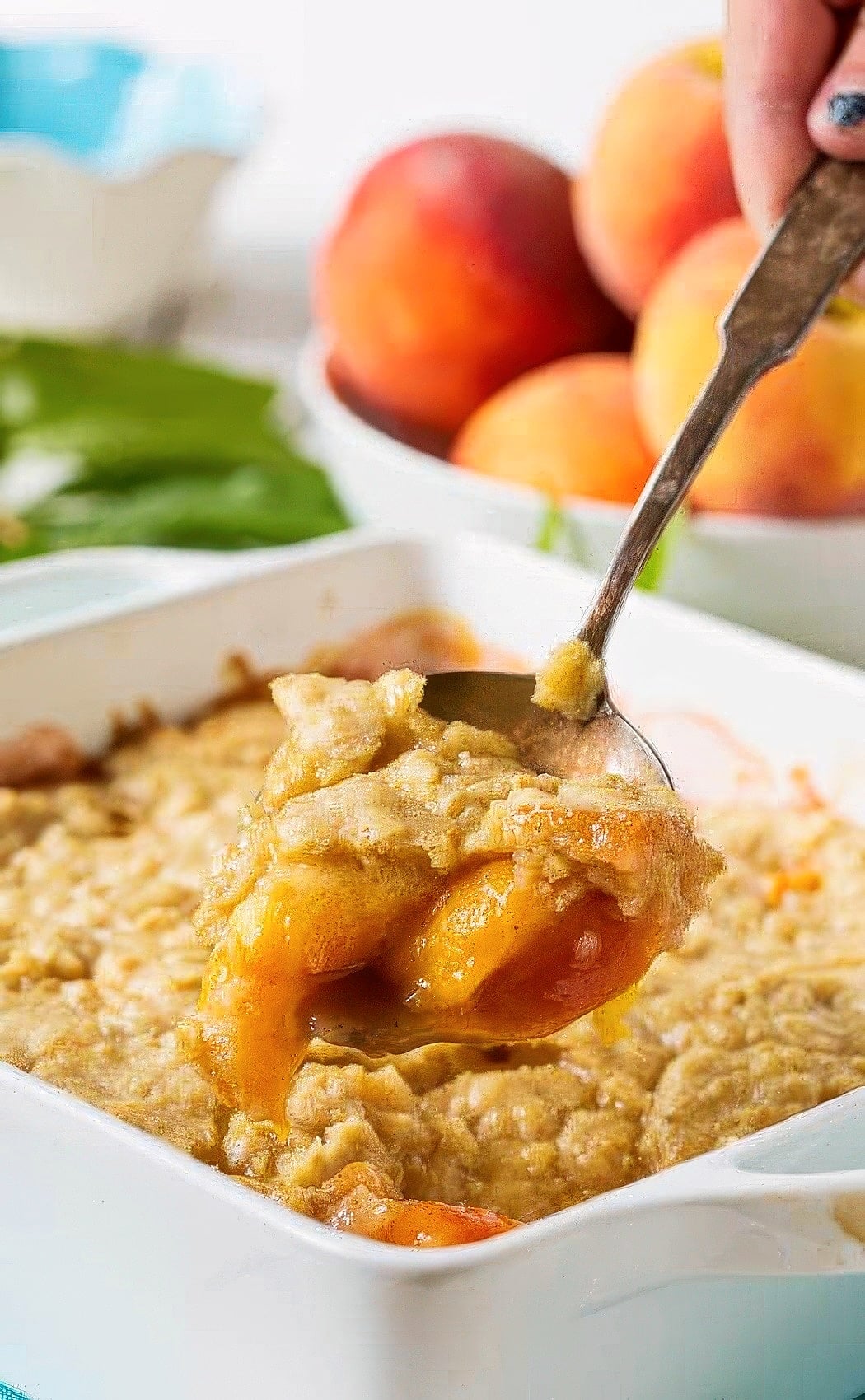 Spoon scooping up Oatmeal Cookie Peach Cobbler.