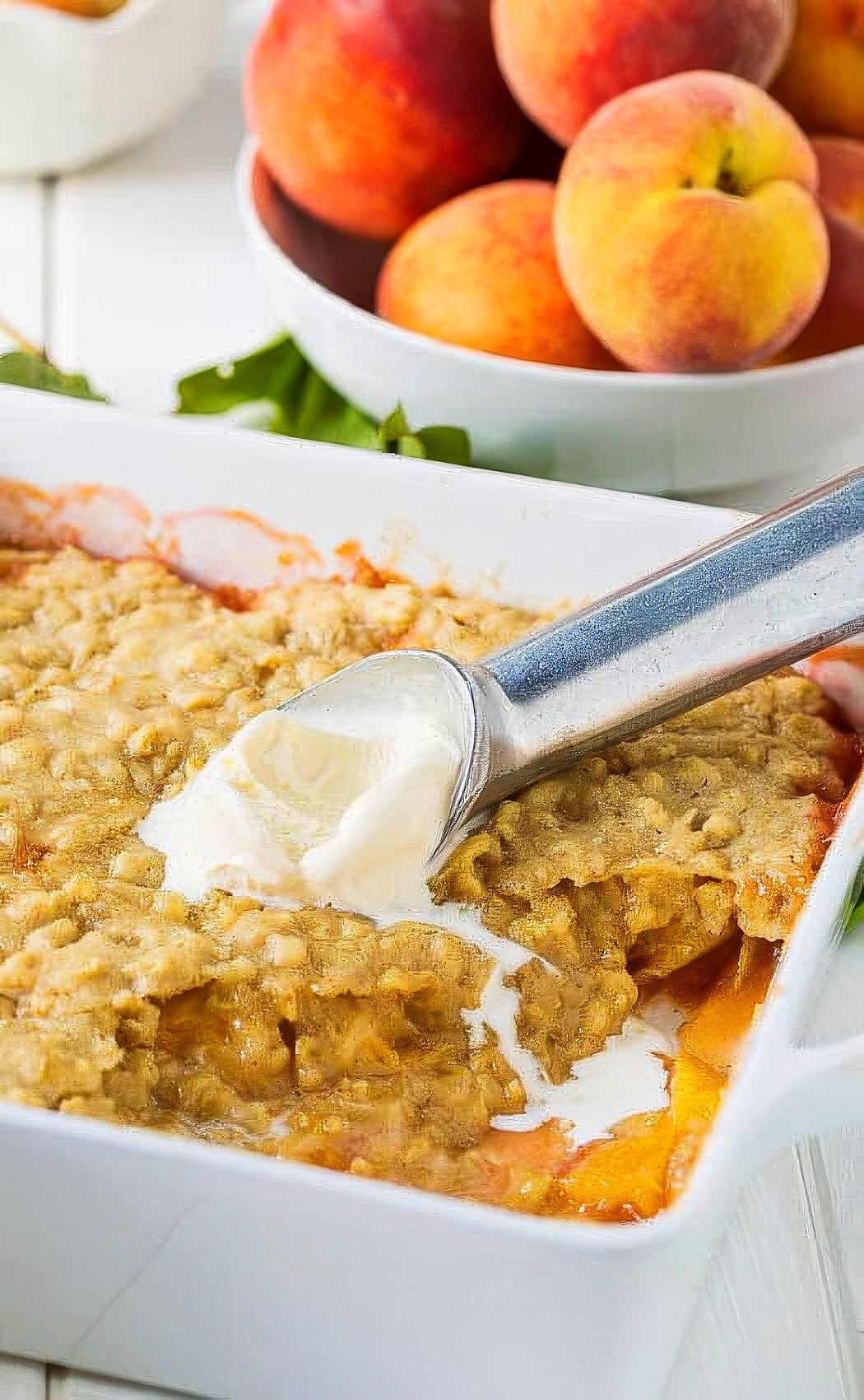 Scoop of vanilla ice cream on top of peach cobbler.