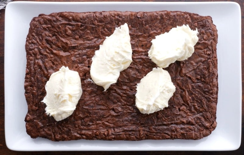 Frosting being spread on brownies.
