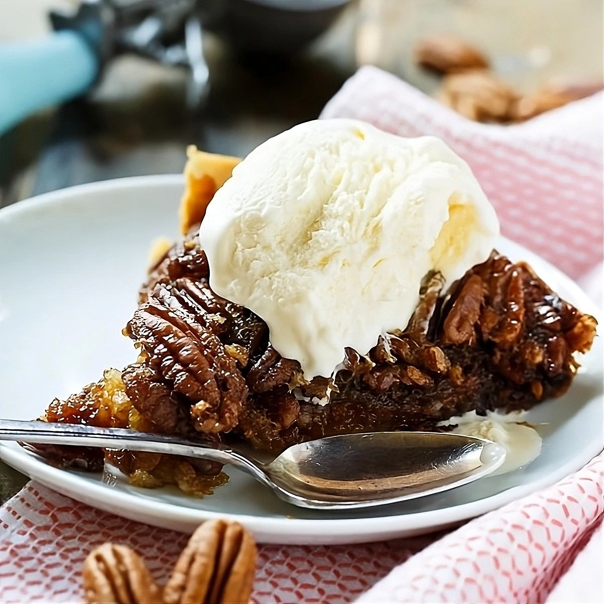 Slice of pecan pie topped with a scoop of vanilla ice cream.