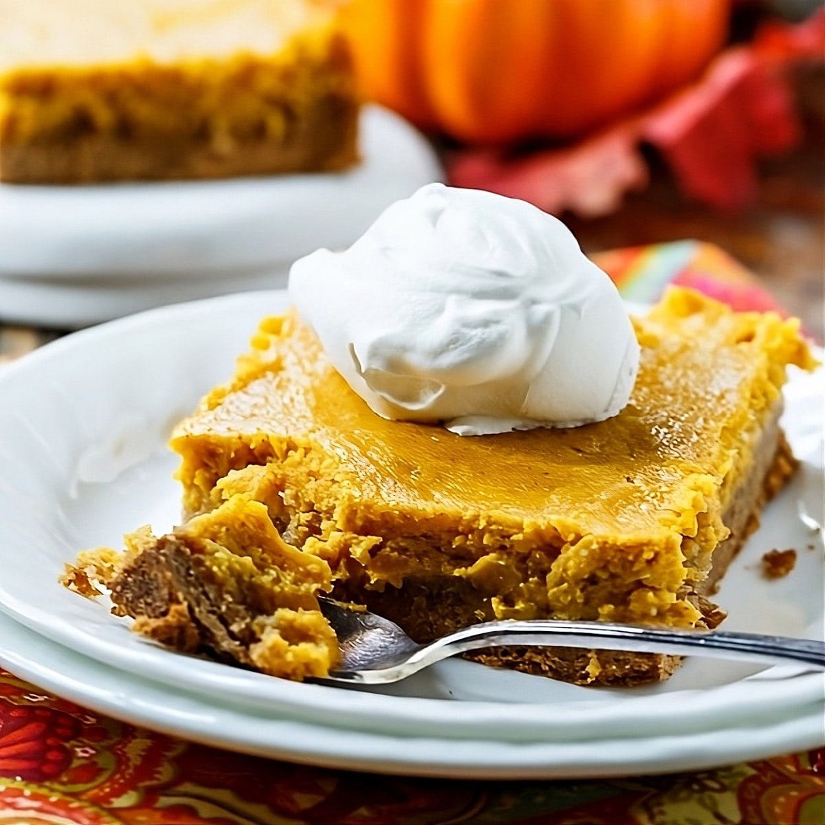 Slice of Pumpkin Spice Gooey Butter Cake topped with whipped cream.