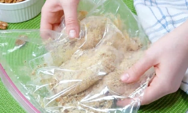 Coating chicken in pecan mixture.