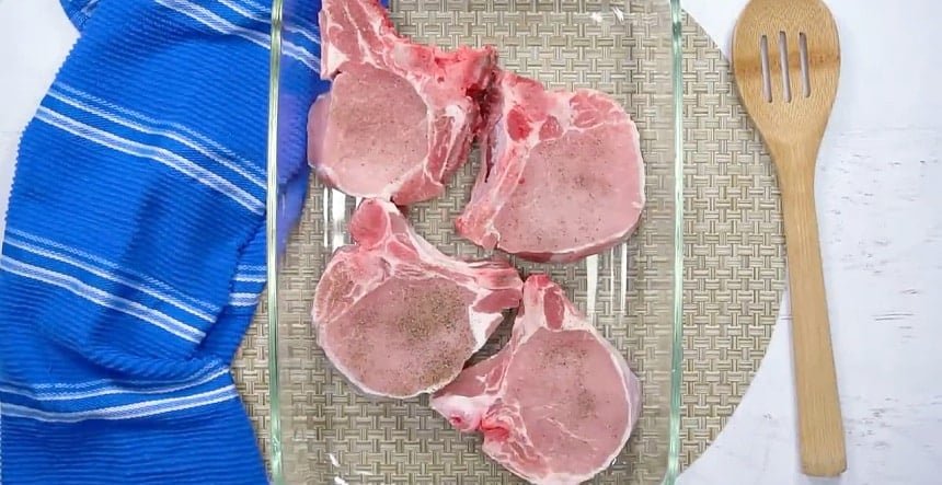 Uncooked pork chops in baking dish.