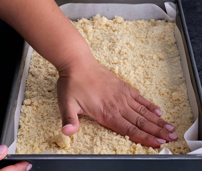 Pressing cookie dough into pan.