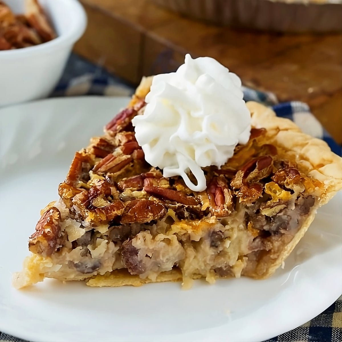 Slice of Cream of Coconut Pecan Pie topped with whipped cream.