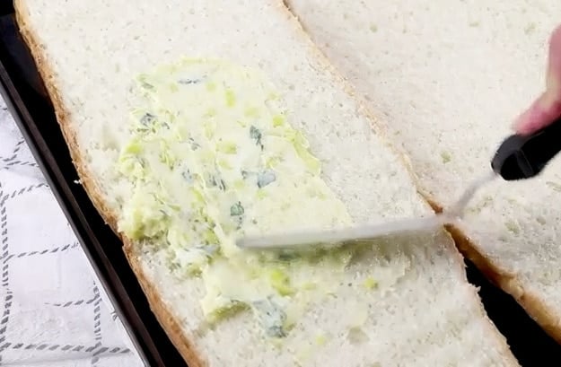 Spreading butter mixture on bread.