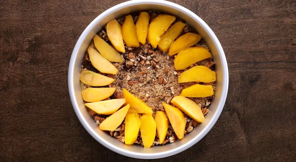 Peach slices added to cake pan.