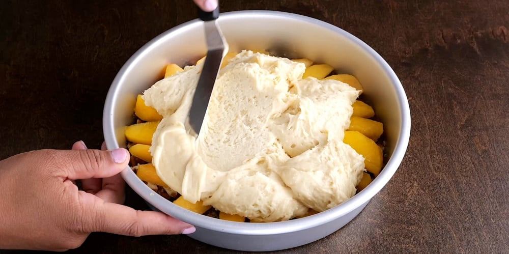 Spreading batter over peaches.