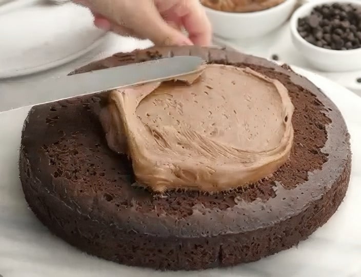Spreading chocolate frosting on cake.