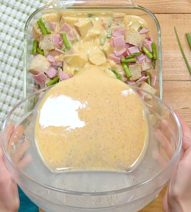 Pouring egg mixture over casserole.