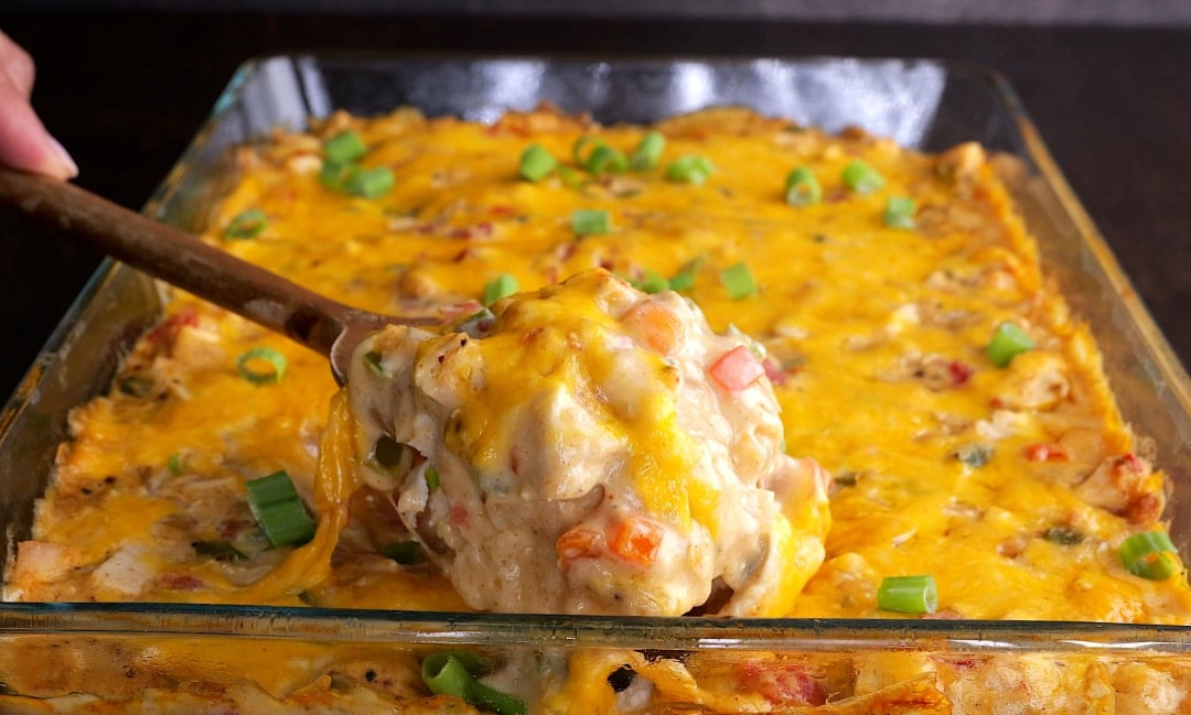 Spoon scooping casserole out of baking dish.