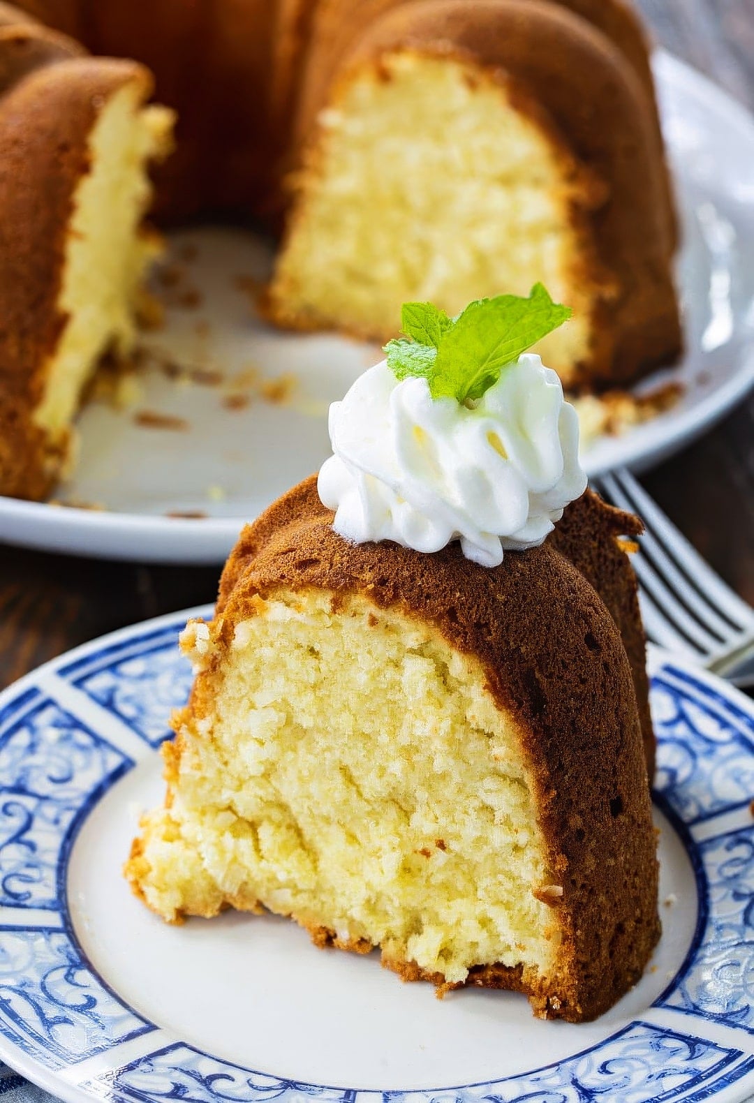 Slice of pound cake topped with whipped cream on a plate.