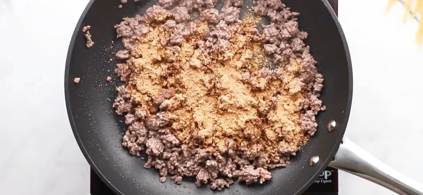 Taco seasoning sprinkled on ground beef.
