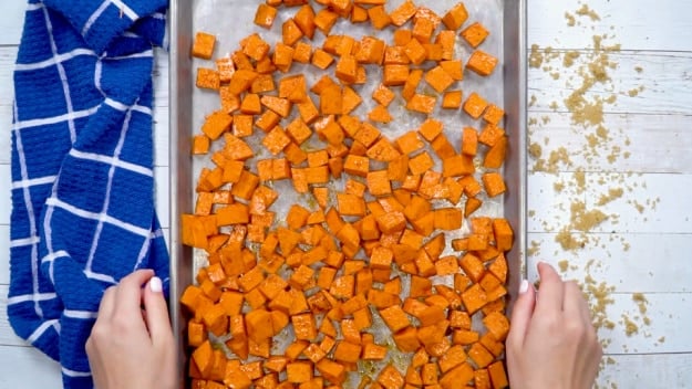 Sweet potato cubes spread out on baking sheet.