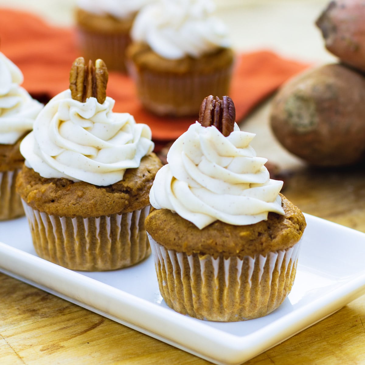 Cupcakes on a serving tray with sweet potatoes in background.