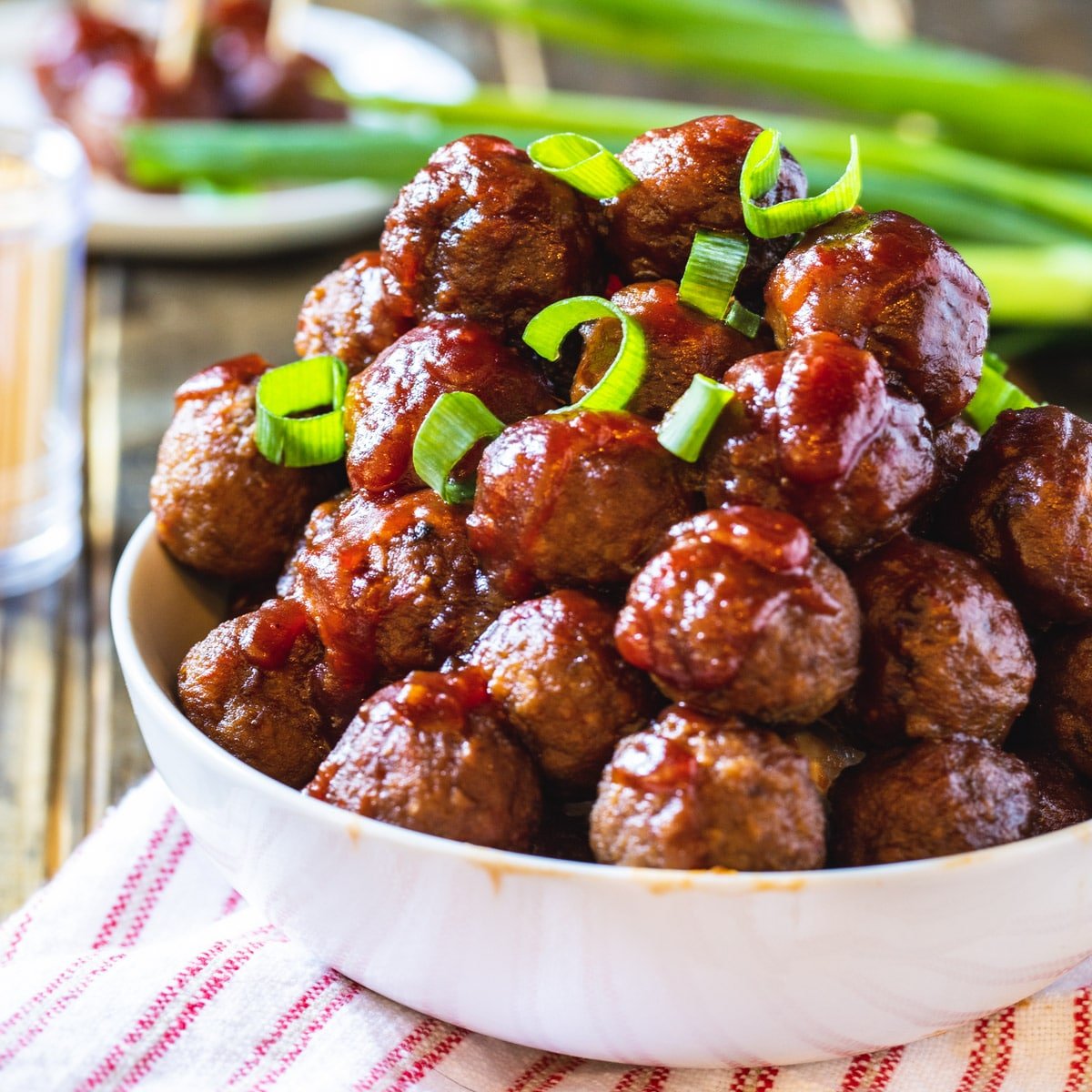 Crock Pot Cranberry Meatballs topped with sliced green onion in a bowl.