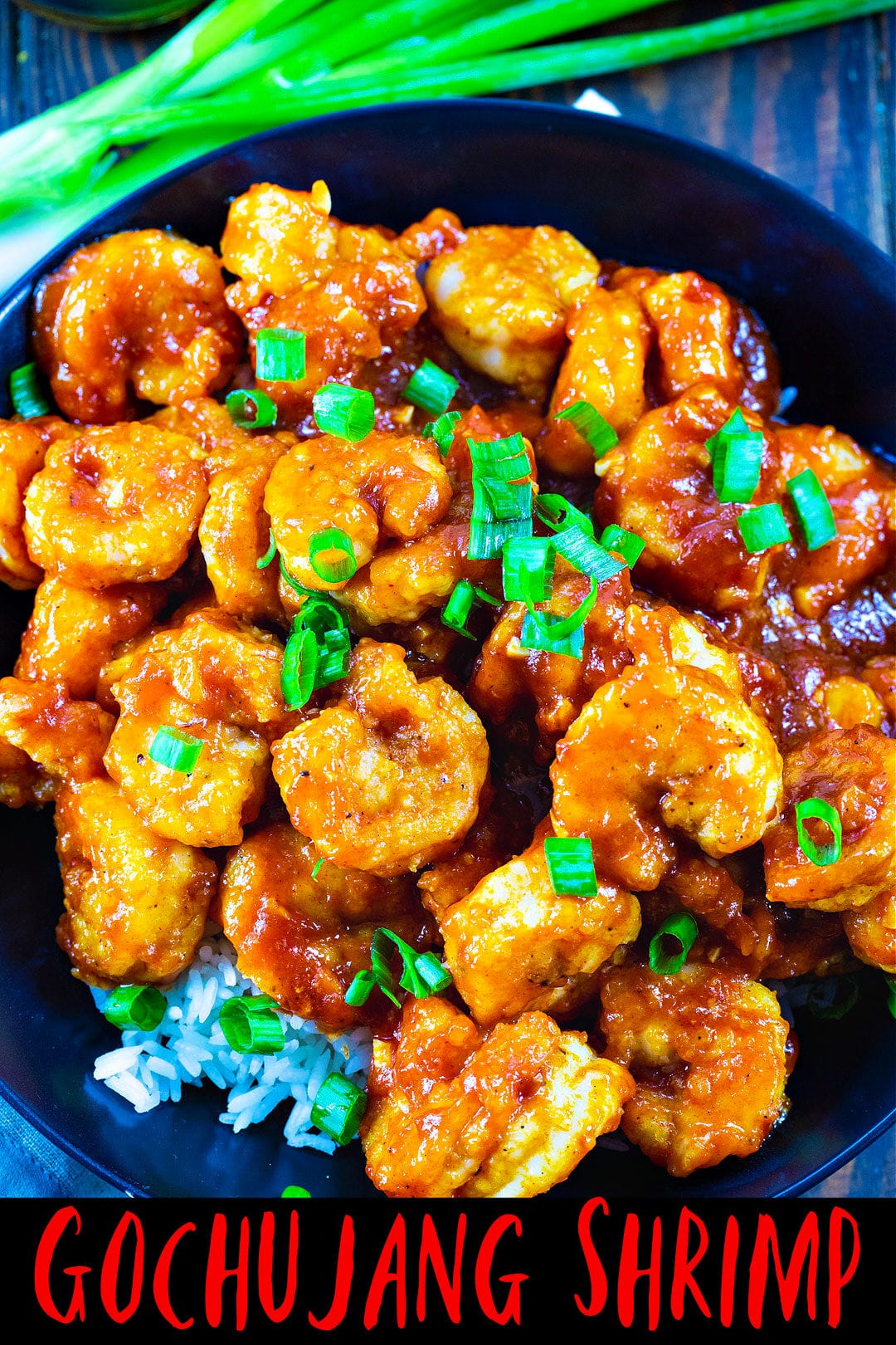 Overhead of shrimp over white rice in a black bowl.