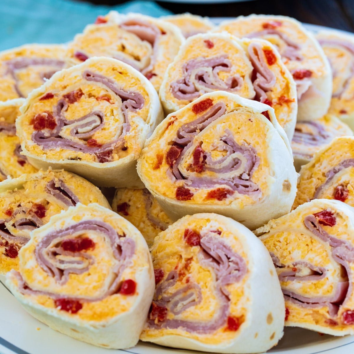 Ham and Pimento Cheese Pinwheels piled up on a plate.