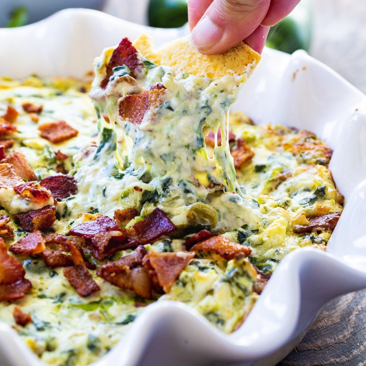 Chip scooping up spinach dip.