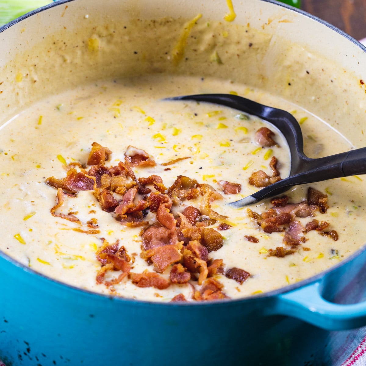 Jalapeno Popper Corn Chowder toped with crumbled bacon in a blue Dutch oven.