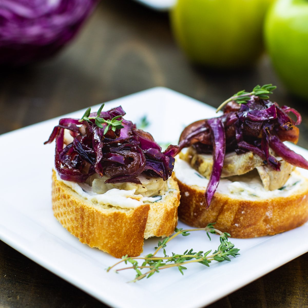 Two pieces of Pork Tenderloin Crostini with Sweet- and Sour Cabbage on a plate.