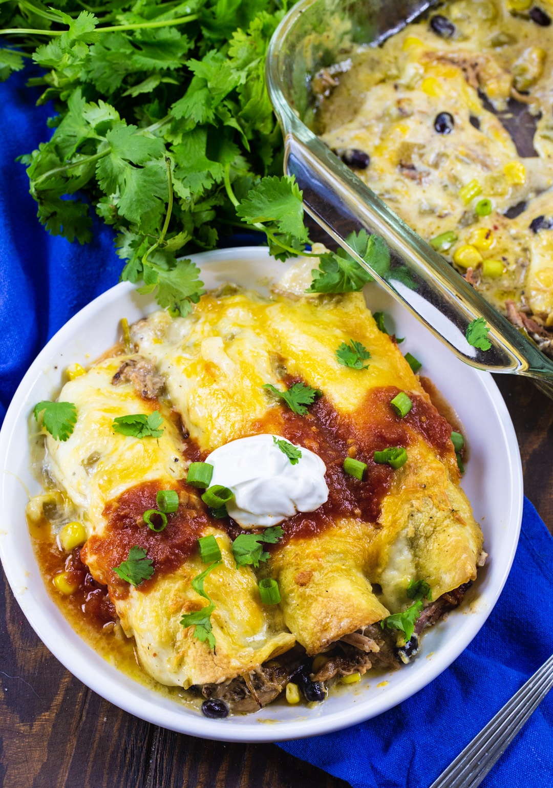 Pulled Pork Enchiladas topped with sour cream on a plate.