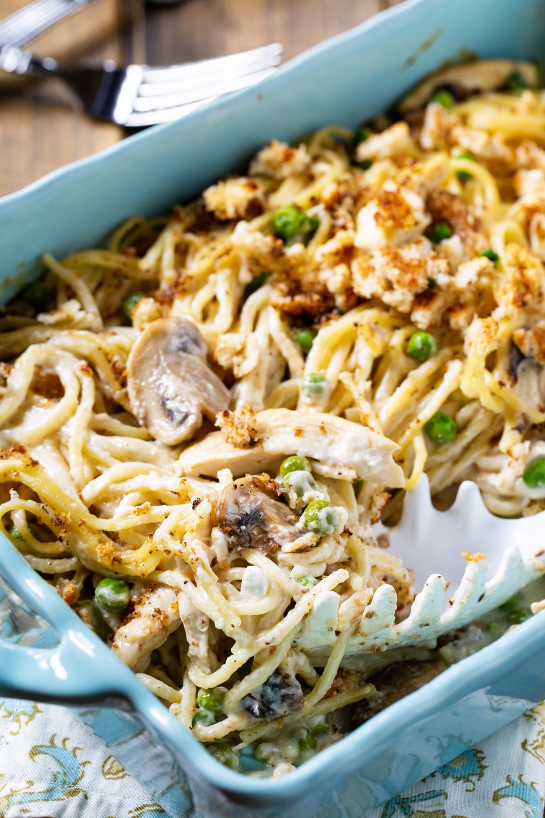 Turkey Tetrazzini getting scooped out of casserole dish.