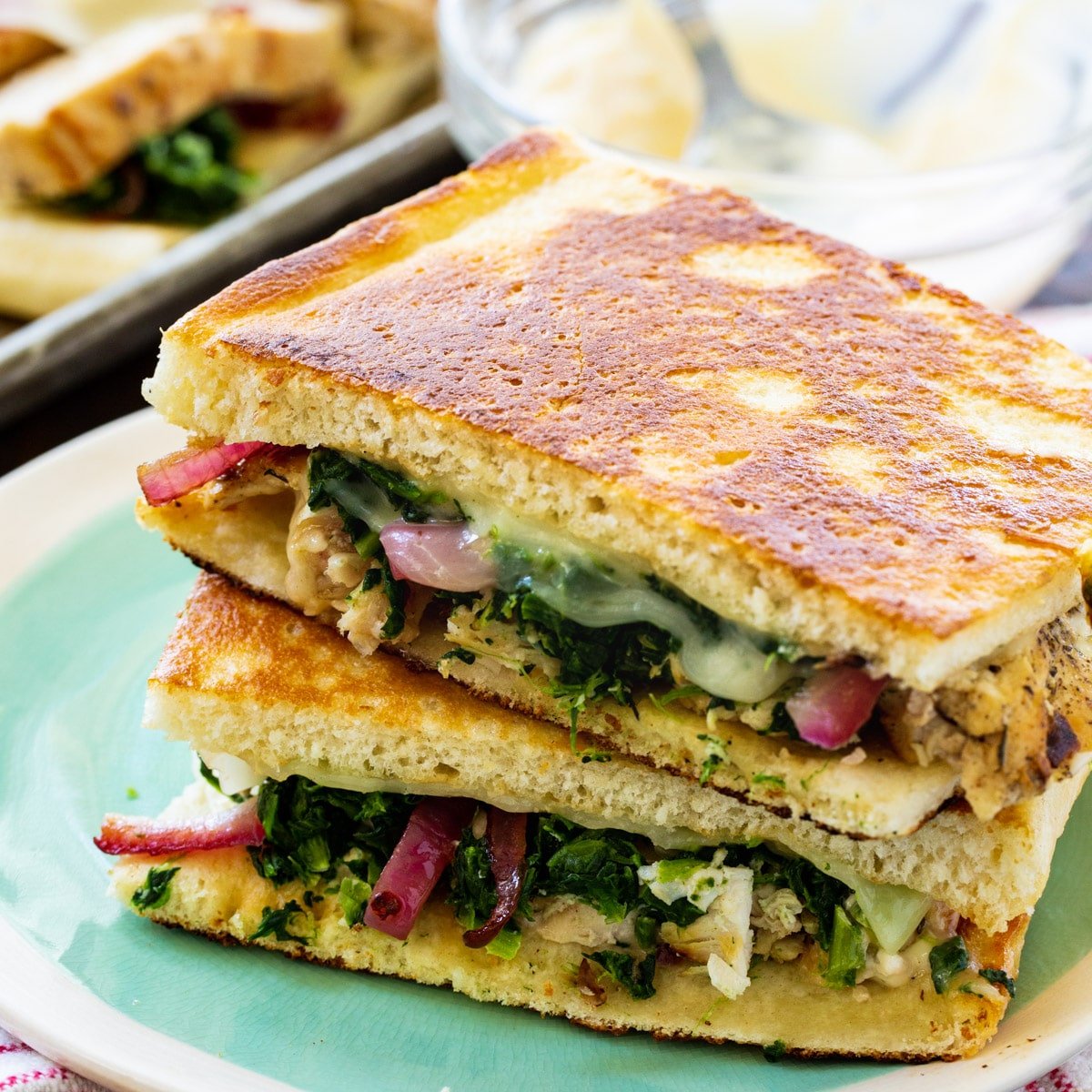 Chicken Florentine Panini halves stacked on a plate.