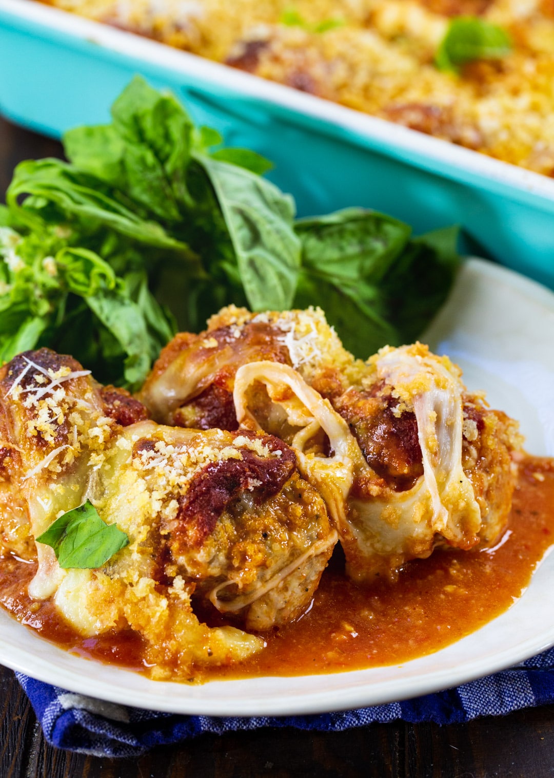 Three Chicken Parmesan Meatballs on a plate with fresh basil.