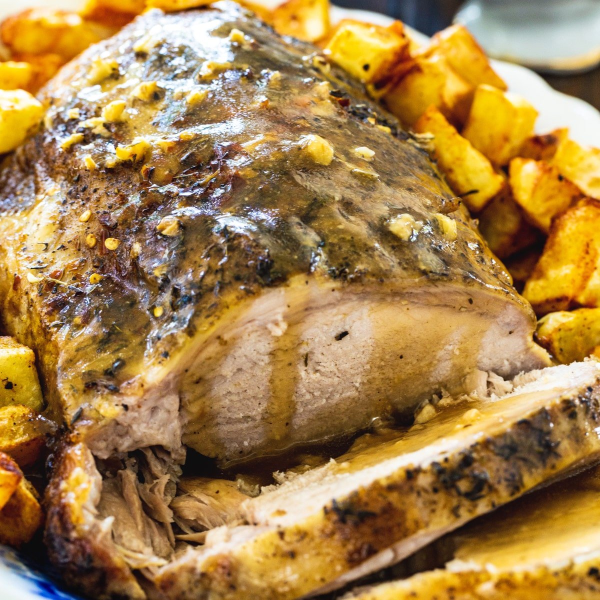 Slow Cooker Garlic Butter Pork Roast surrounded by roasted potatoes.