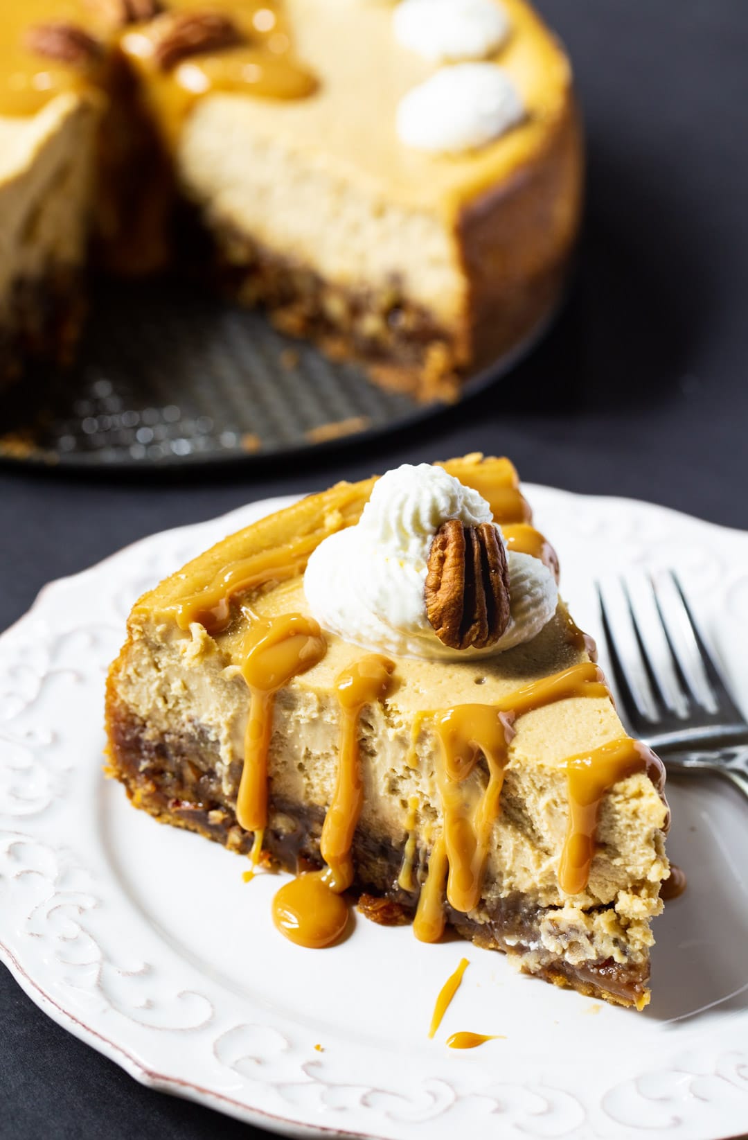 Pecan Pie Cheesecake slice with rest of cheesecake in background.