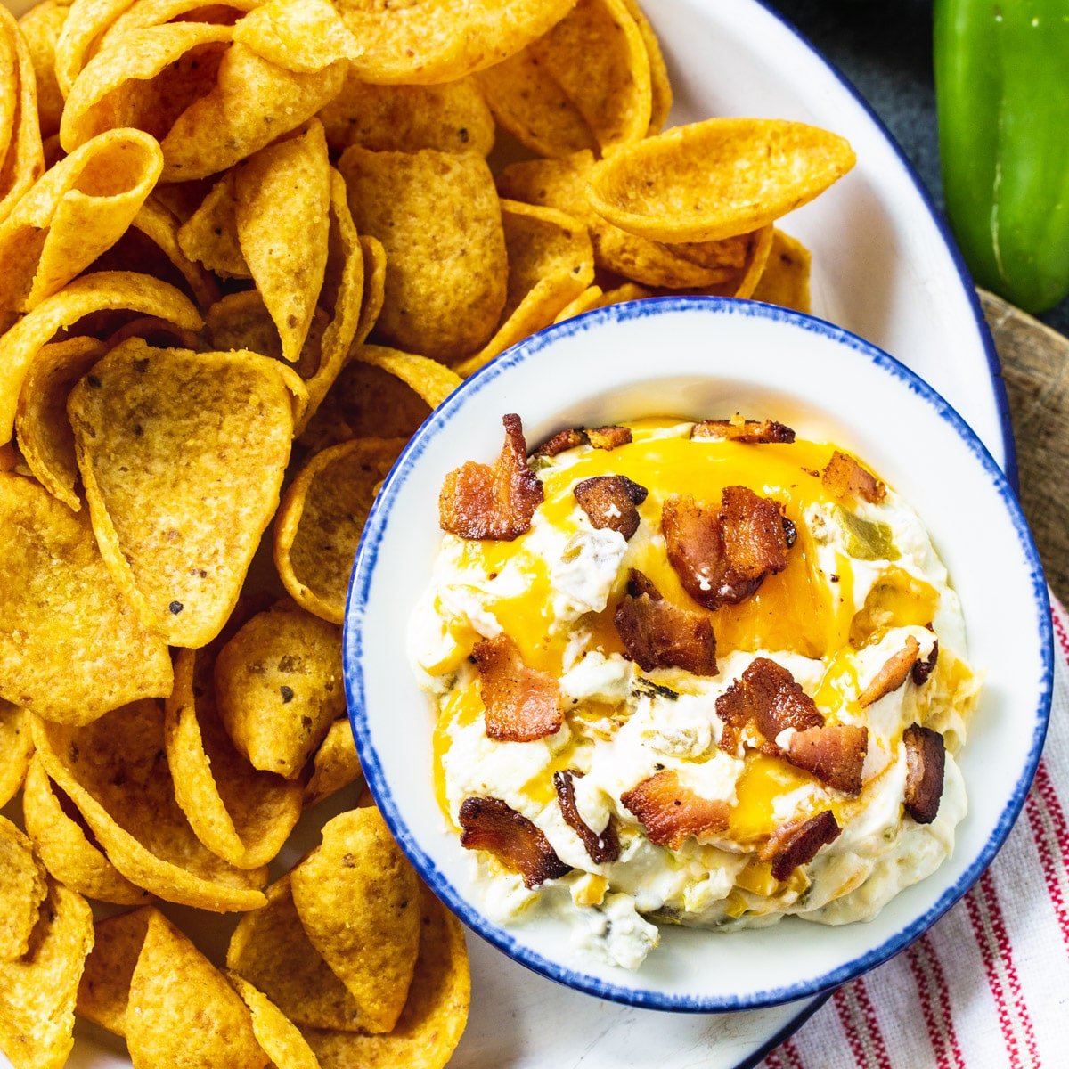Slow Cooker Jalapeno Popper Dip in a bowl surrounded by Fritos.