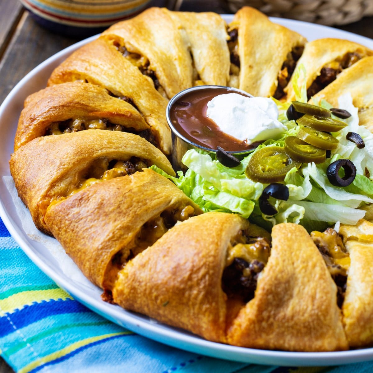 Taco Ring on a plate with salsa, lettuce, and jalapenos in middle of ring.