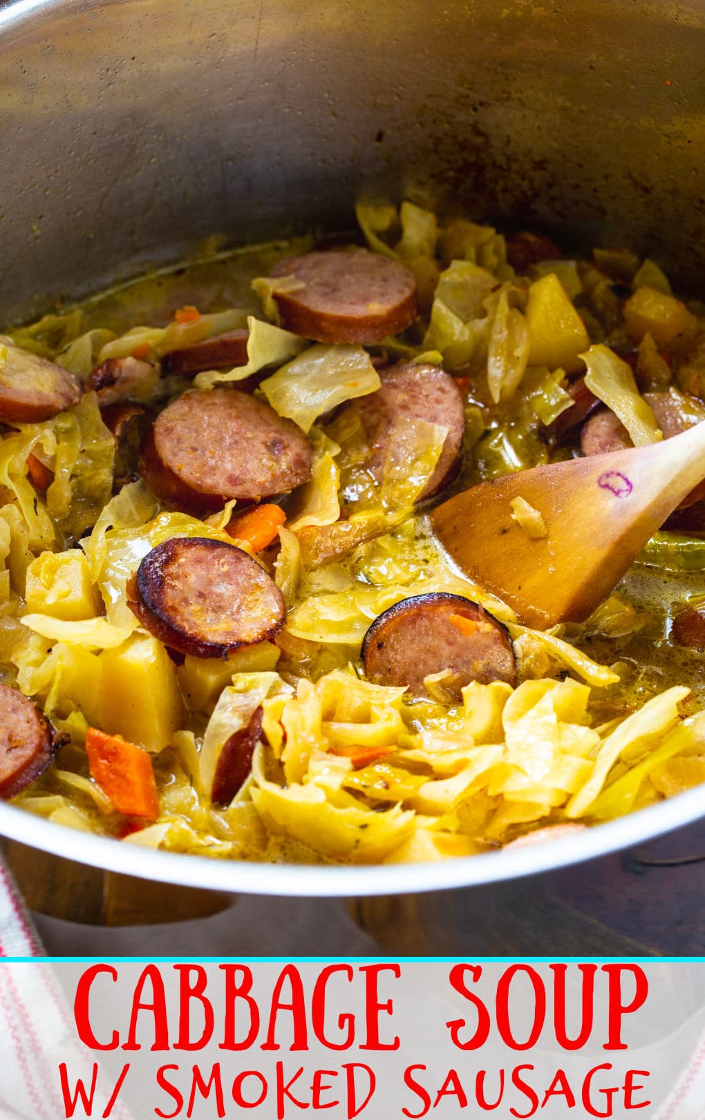 Wooden spoon scooping Cabbage Soup with Smoked Sausage.