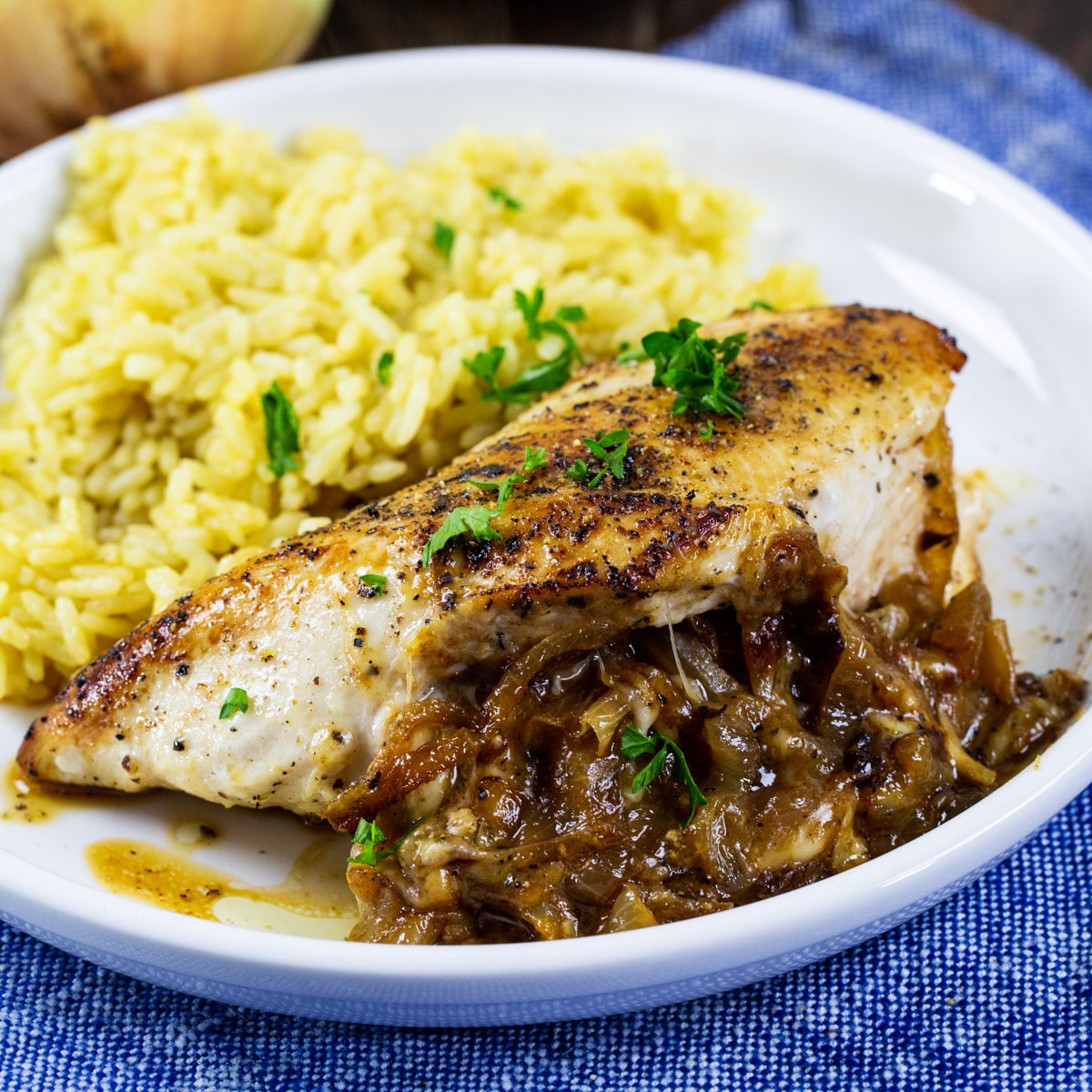 Piece of French Onion Stuffed Chicken on plate with rice.