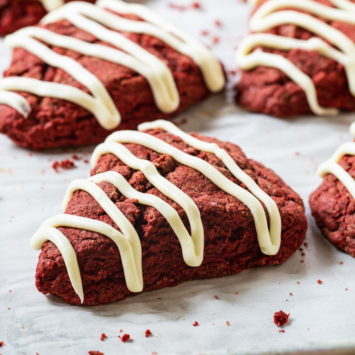 Red Velvet Scones with Cream Cheese Glaze on parchment paper.