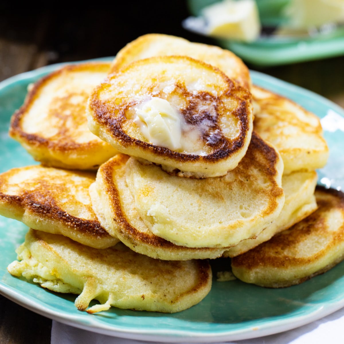 Hoe Cakes piled on a plate and topped with butter.