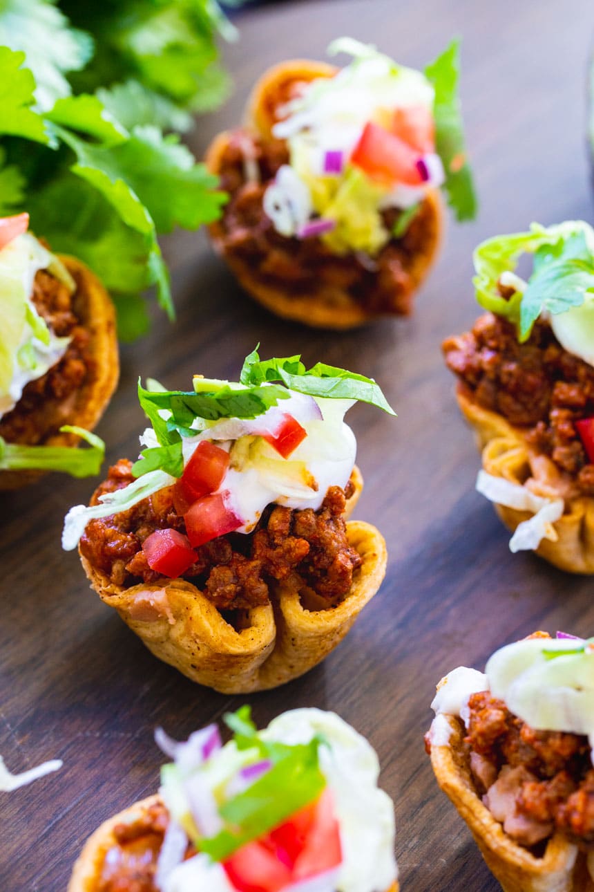 Mini Taco Bites on wood tray with bunch of cilantro.