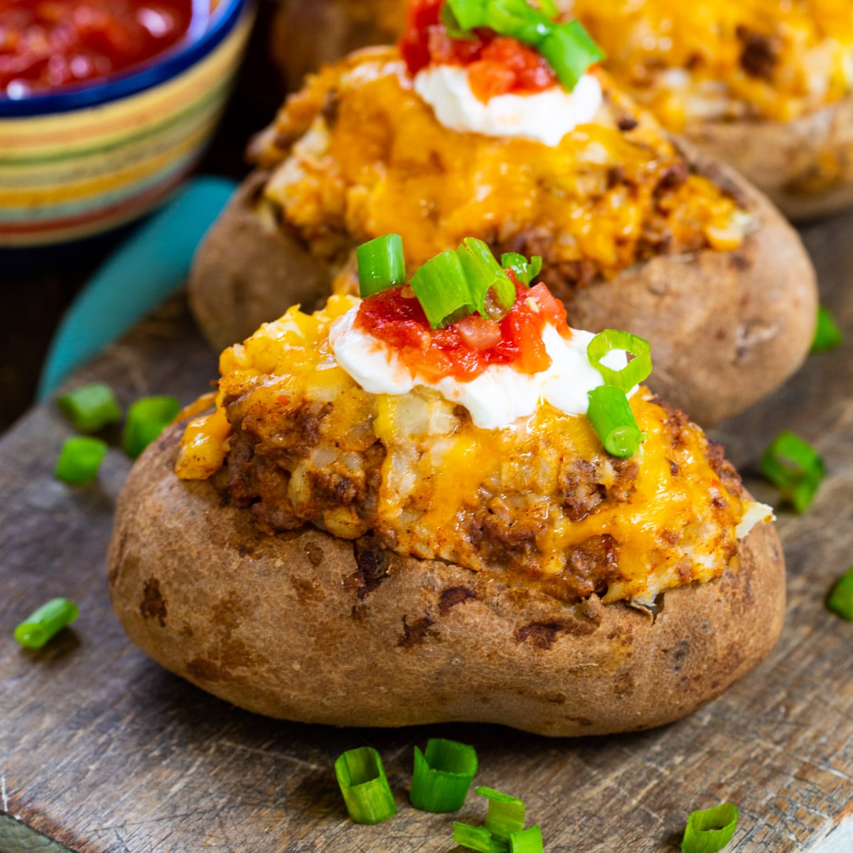 Three Double Stuffed Taco Potatoes on a wood cutting board.