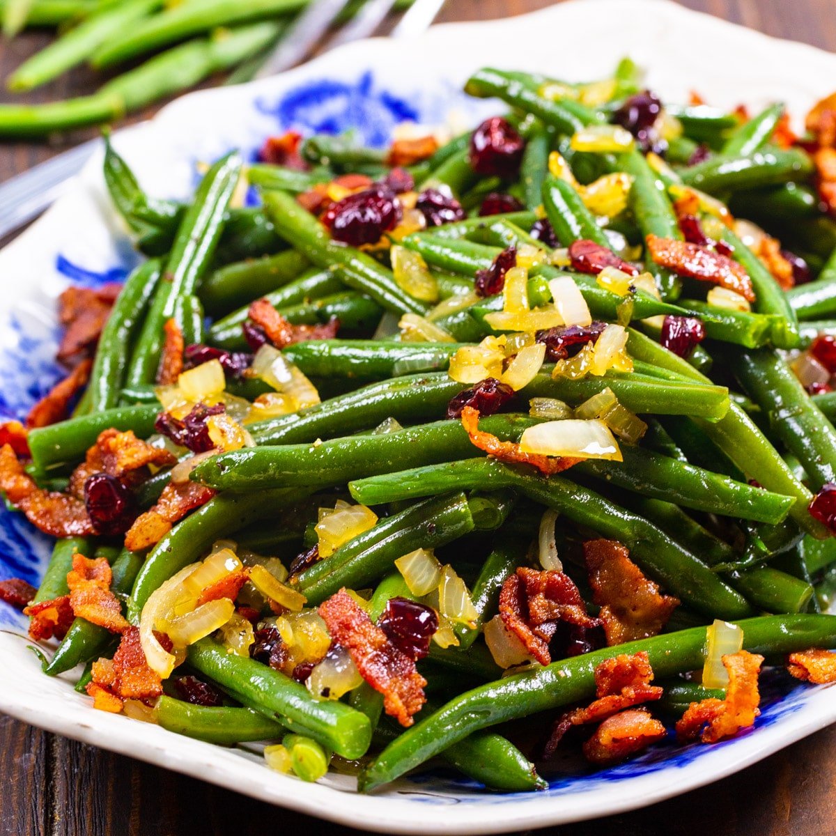 Maple-Glazed Green Beans topped with crumbled bacon on a serving platter.