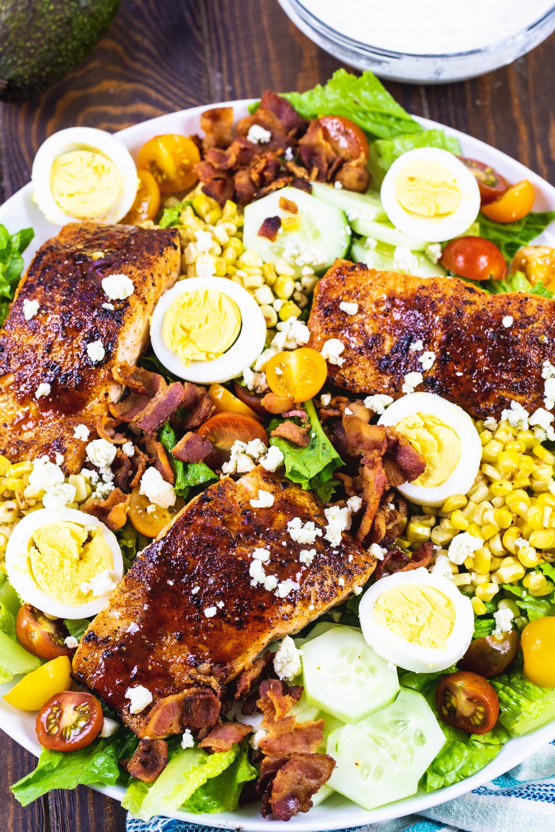 Cobb Salad topped with salmon on a large plate.