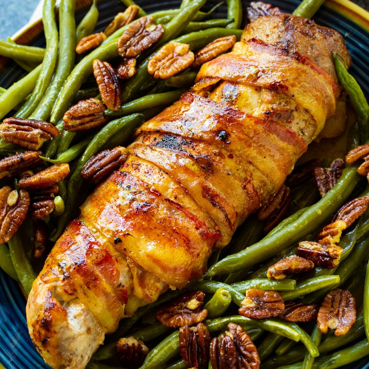 Bacon-Wrapped Pork Tenderloin on a plate with green beans.