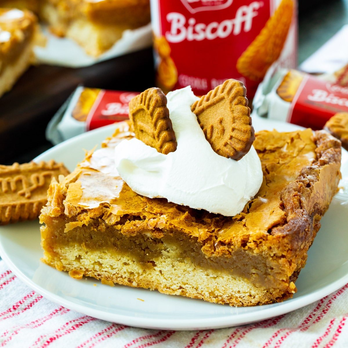 Biscoff Gooey Butter Bar topped with whipped cream on a plate.