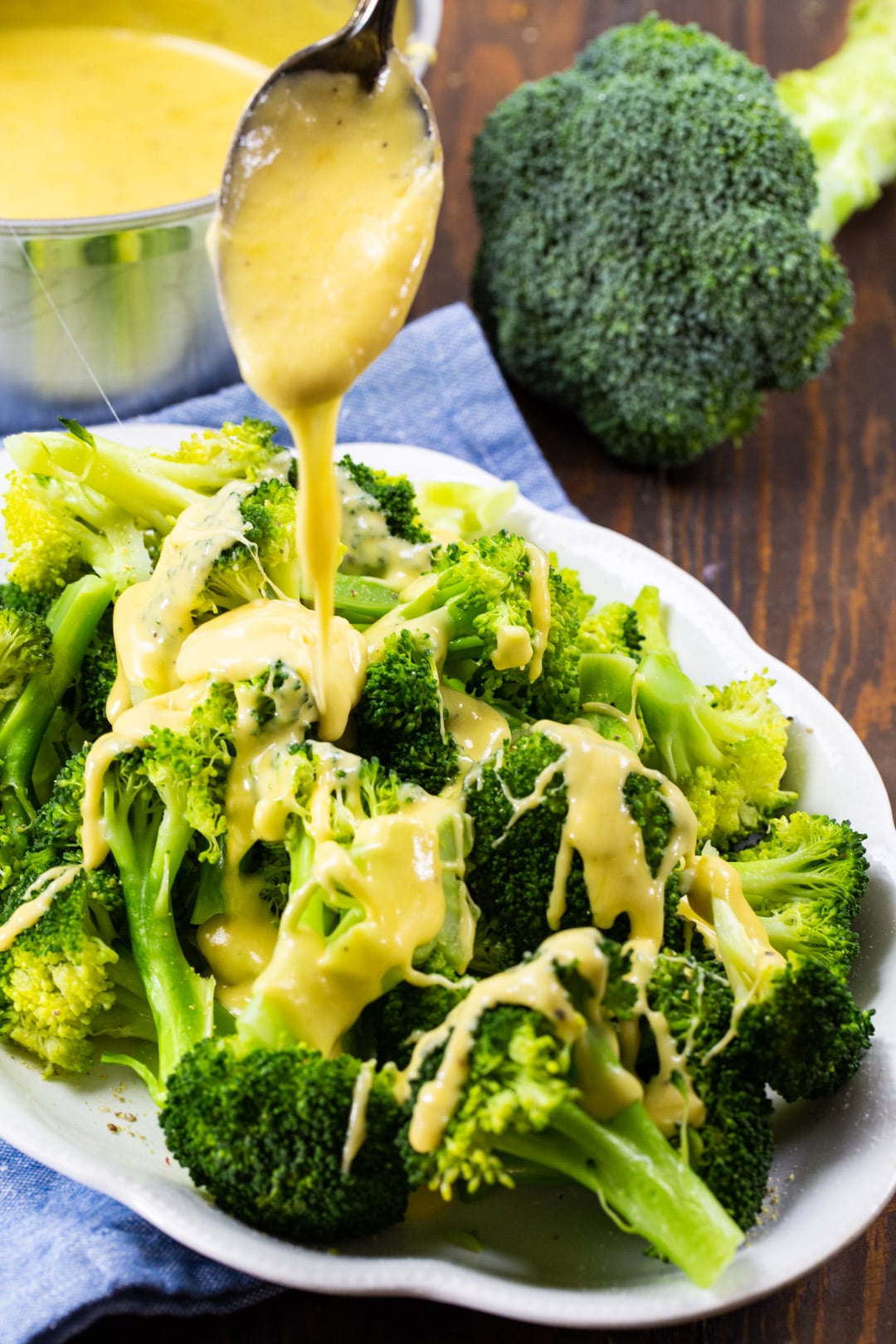 Cheddar sauce getting drizzled on broccoli.