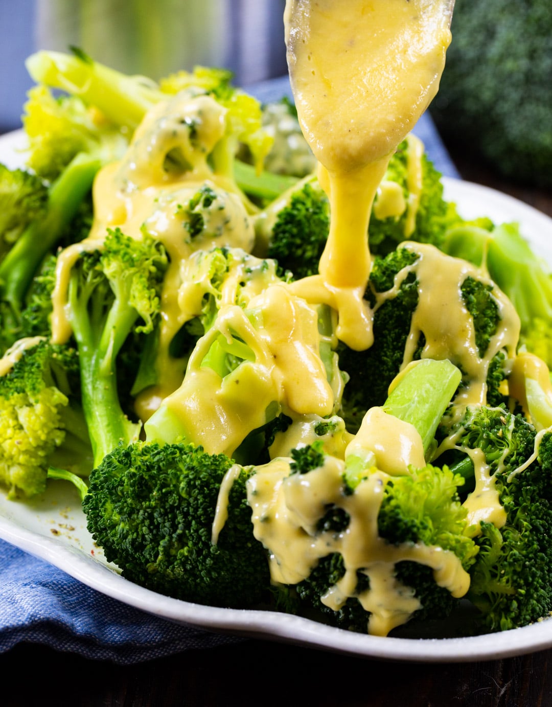 Cheese sauce being drizzled on broccoli.