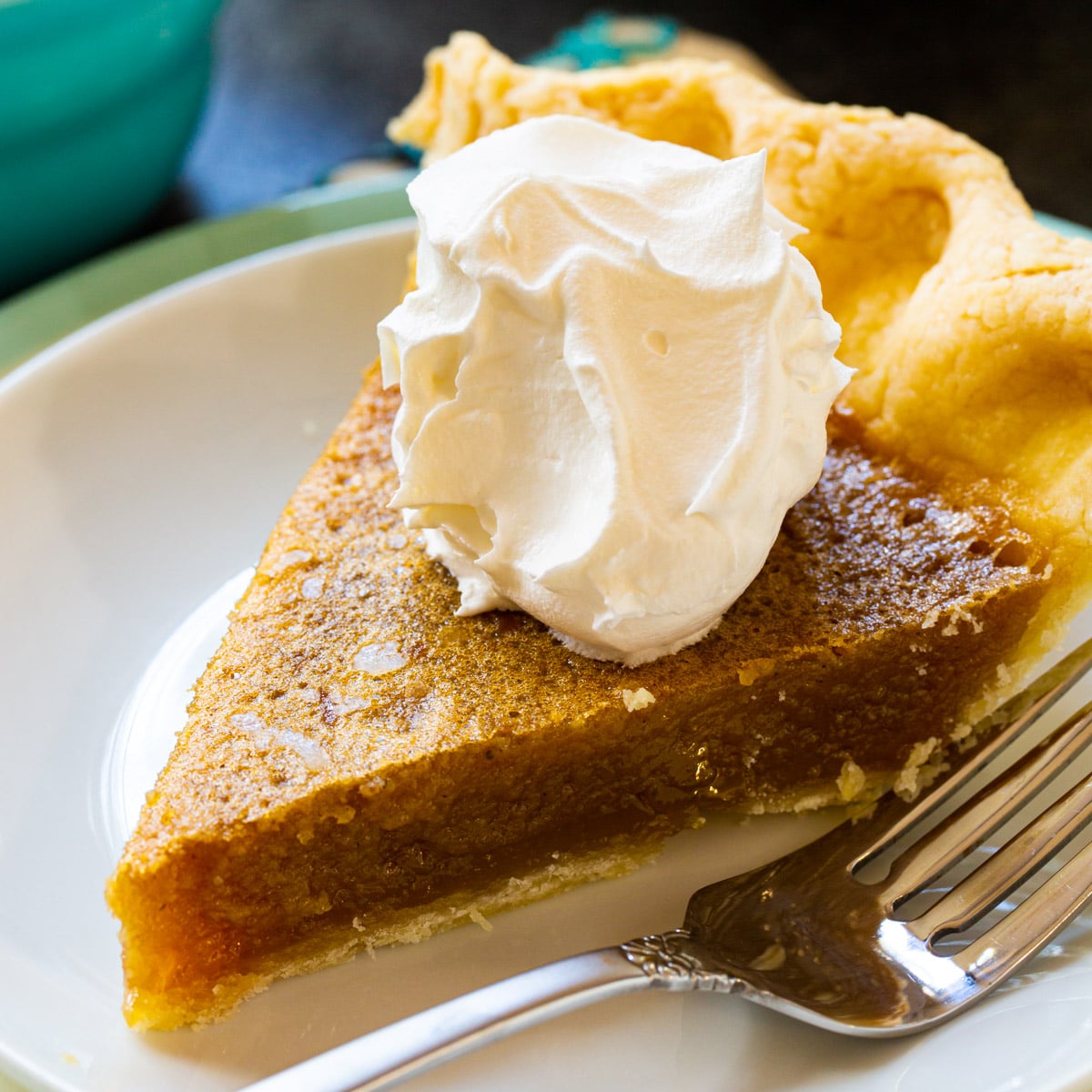 Slice of caramel chess pie topped with whipped cream.